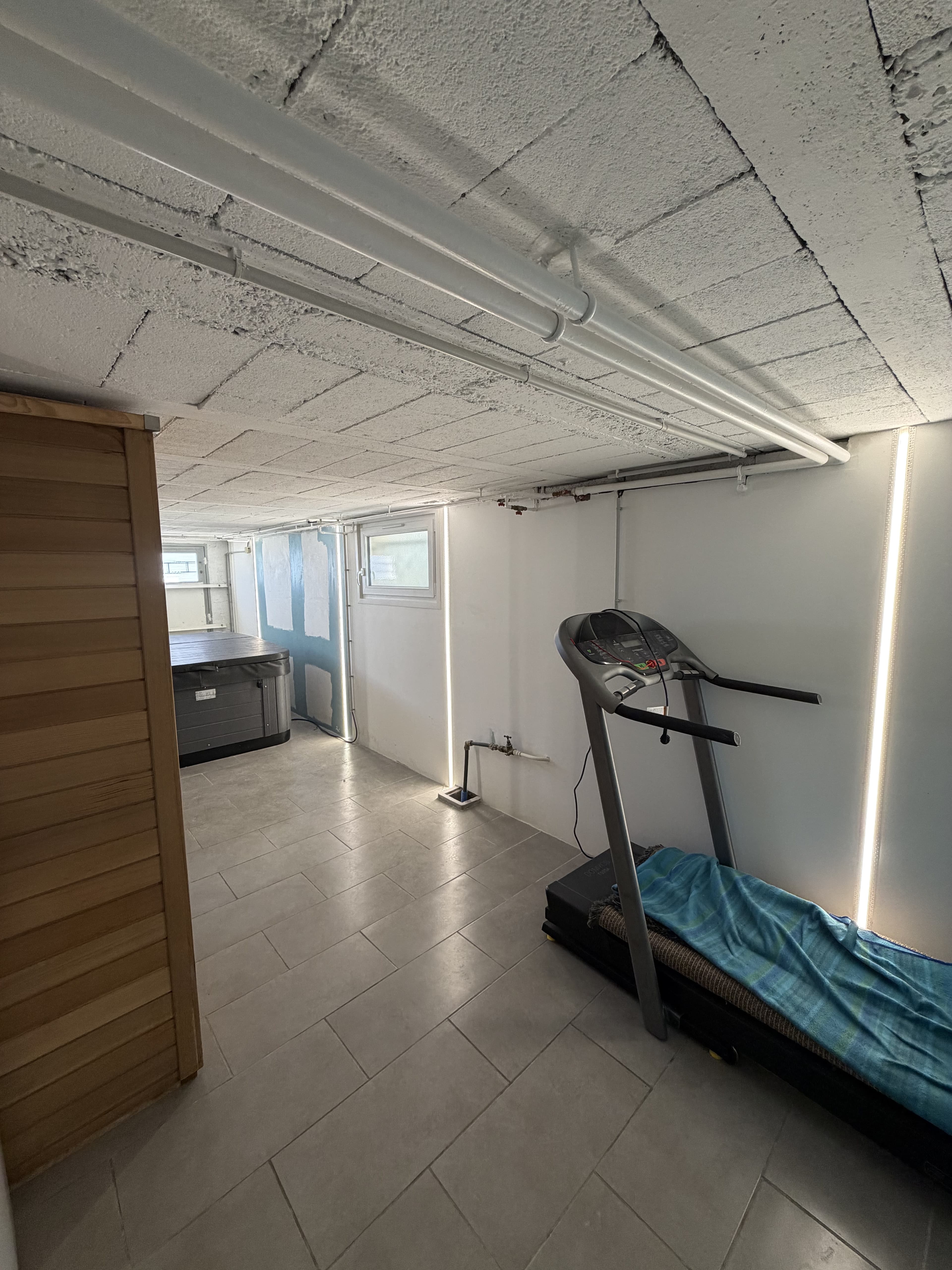 Éclairage tubes apparents au plafond d'une cave aménagée en espace fitness par CT elec, Marne